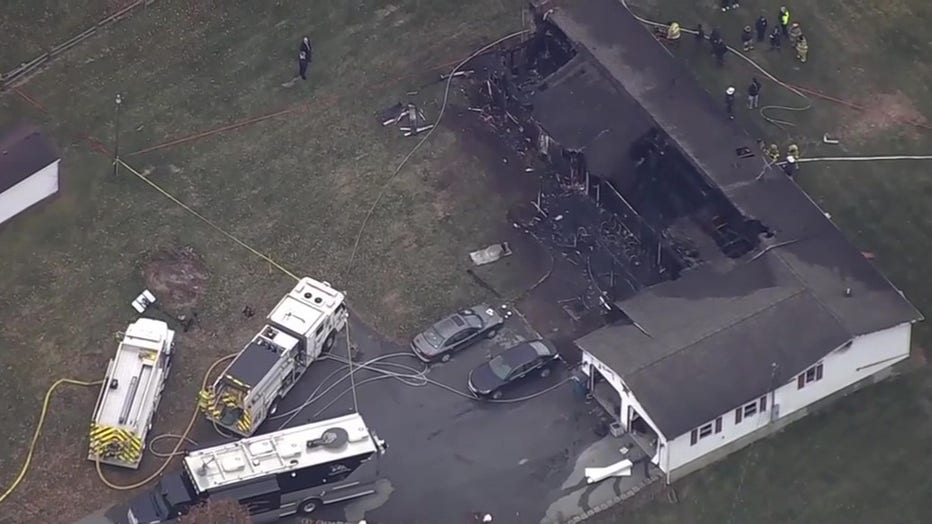 An overhead view of a house destroyed by a fire with police tape and fire trucks seen near the home.