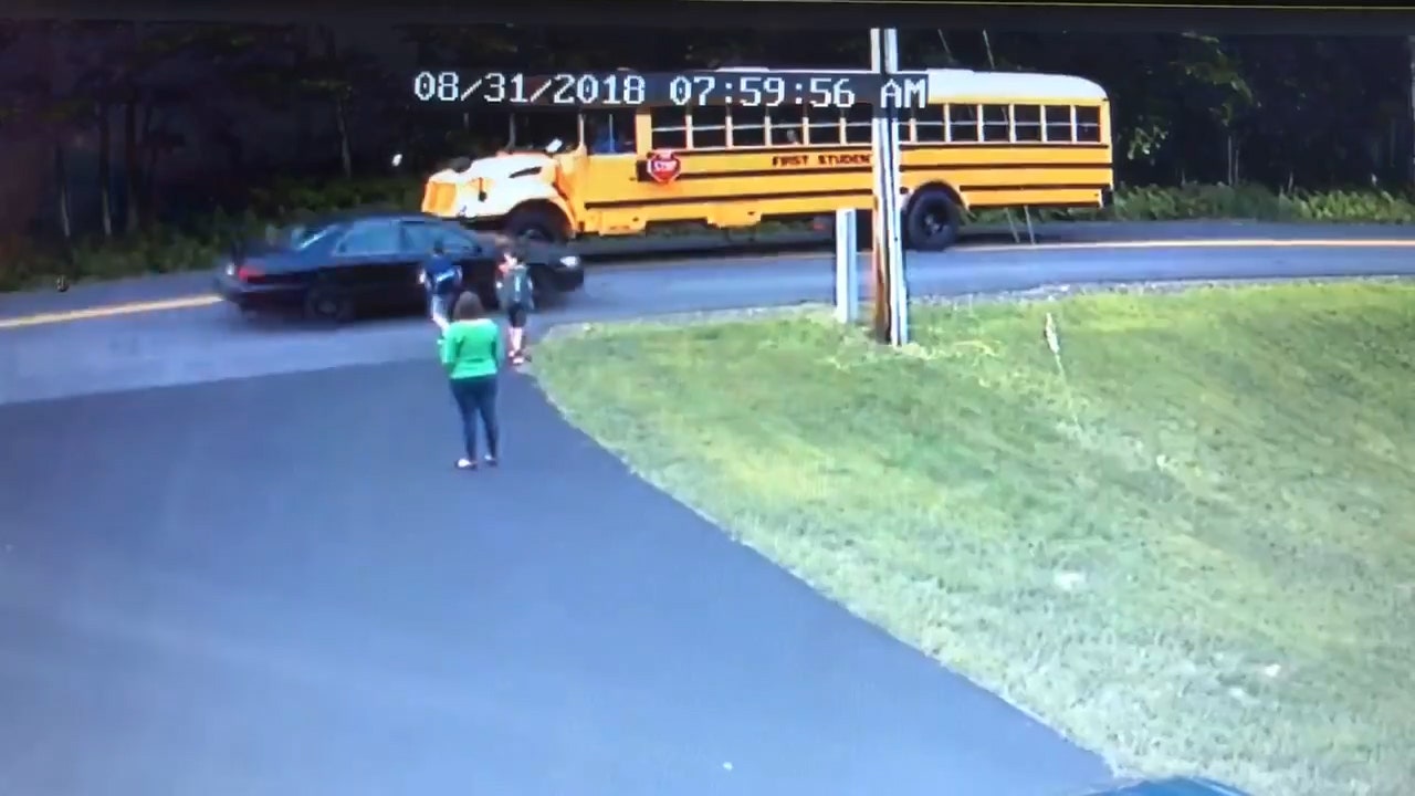 Young boy nearly hit by car while crossing road for school bus