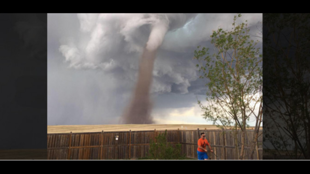 Man calmly mows lawn during tornado