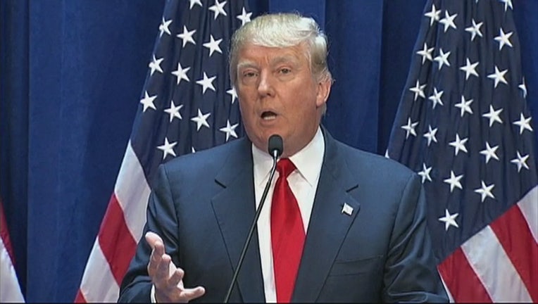Donald Trump speaks into a microphone with American flags behind him