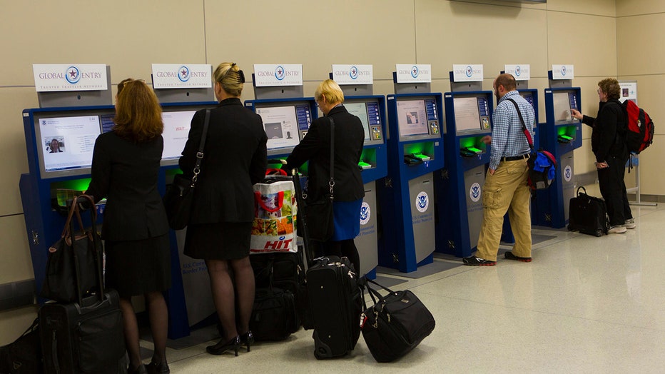 Travelers using Global Entry kiosks.