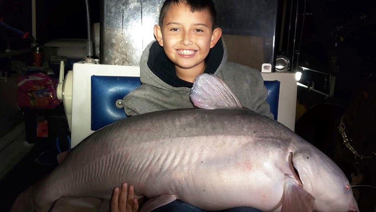 Smiling boy holding a massive catfish