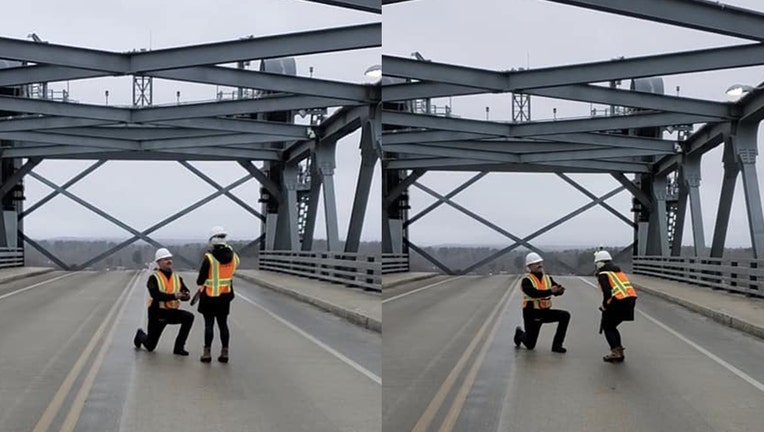 Kneeling man proposes to woman on a bridge