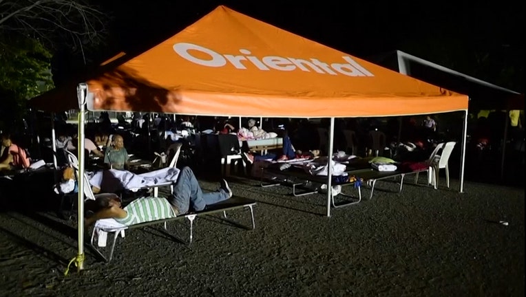 Residents rest on cots under a tent