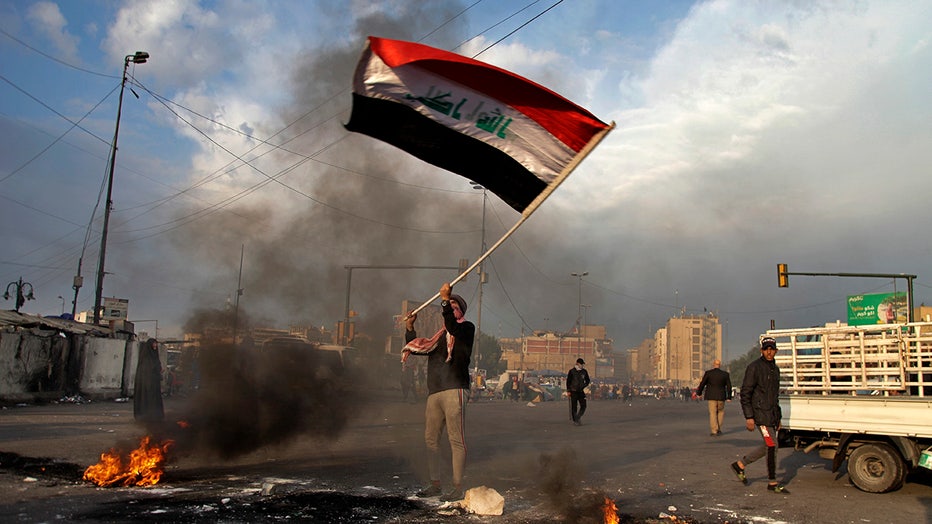 A protester waves the national flag in Baghdad, Iraq