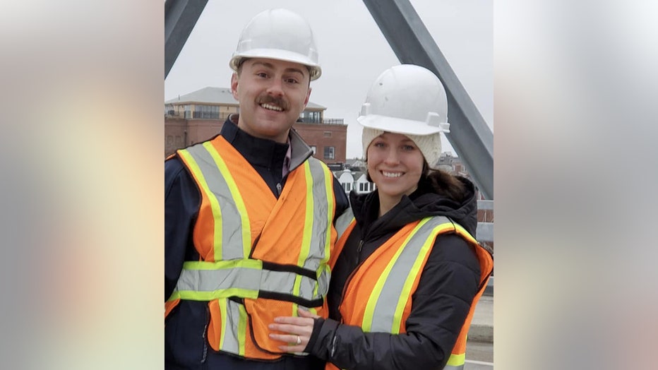 Man and woman wearing hardhats and safety vests smile