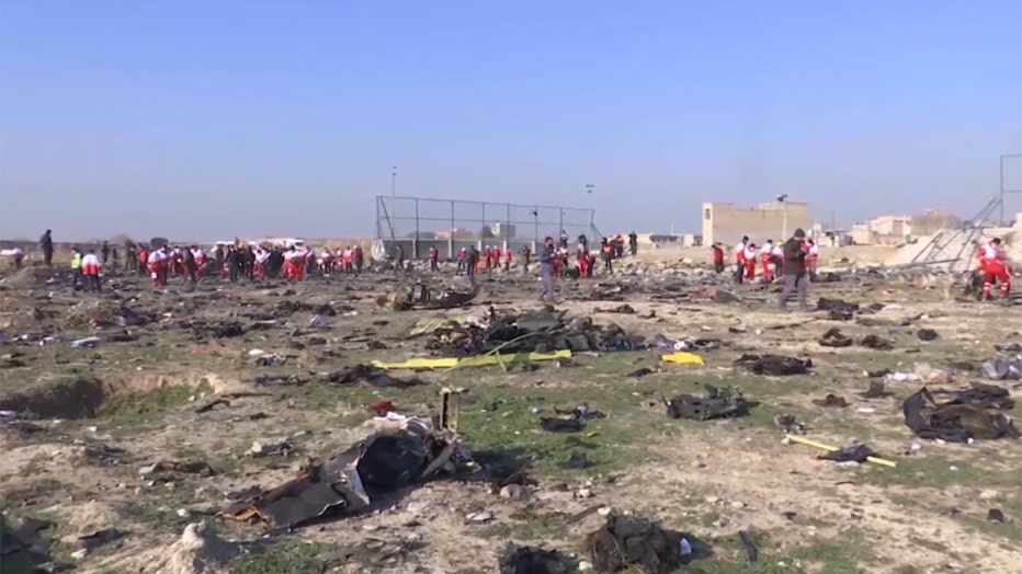 Dozens of responders examine a field of debris near Tehran