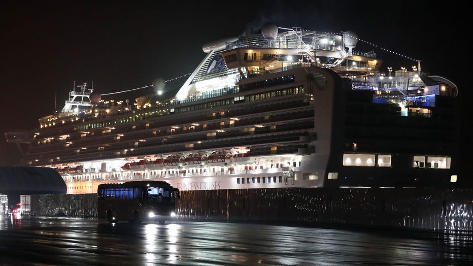 A bus carrying U.S. citizens leaves the Daikaku Pier Cruise Terminal in Yokohama port, next to the Diamond Princess cruise ship, with people quarantined onboard due to fears of the new COVID-19 coronavirus, on Feb. 17, 2020. (Photo by BEHROUZ MEHRI/AFP via Getty Images)