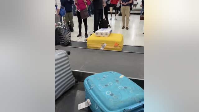 Toilet paper seen attached to luggage on carousel