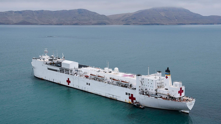 Navy hospital ship Comfort with white hull anchored off Peru with coast and mountains behind it
