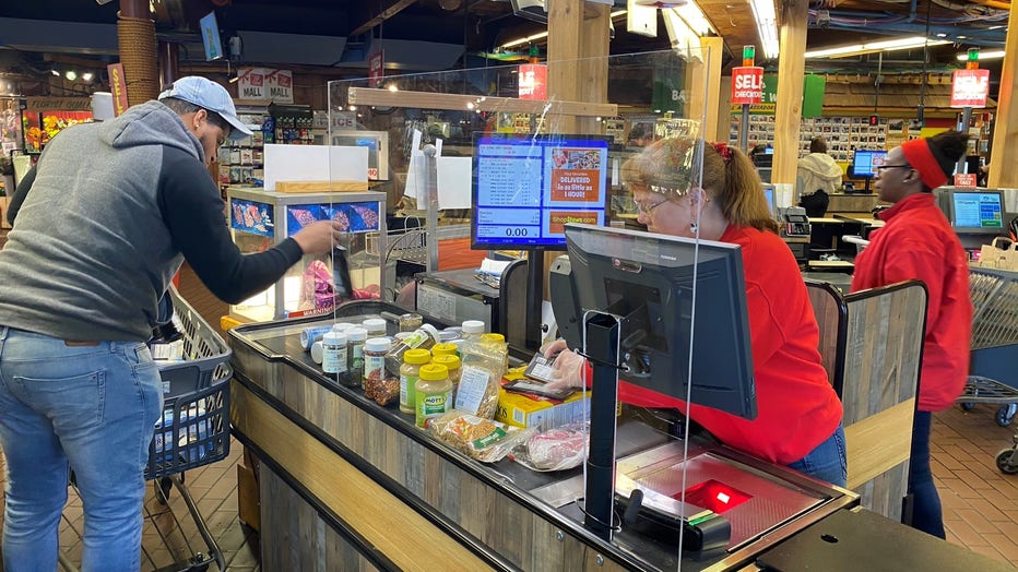 A transparent protective barrier separates the cashier from the shoppers at a Stew Leonard's supermarket.