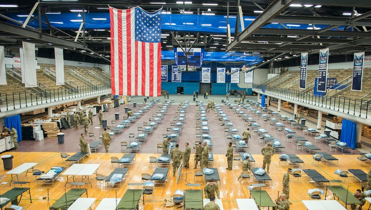 National Guard troops set up medical equipment inside a college sports arena