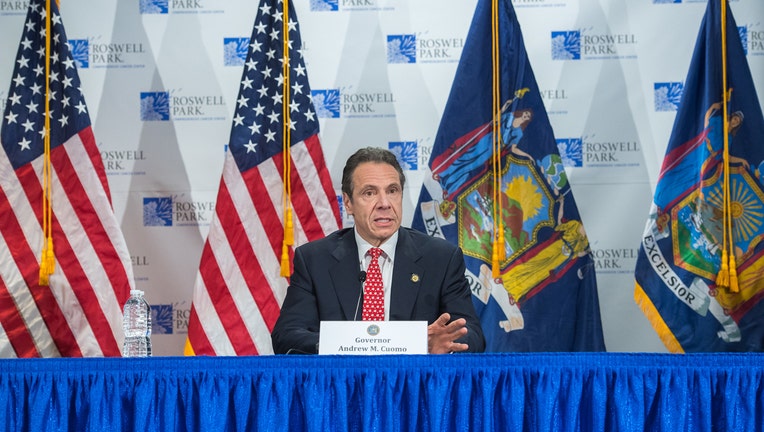 Gov. Cuomo at a table with U.S. and New York flags behind him