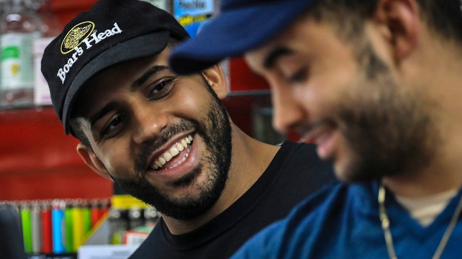 Brothers Alex Batista and Eudis Batista smile as they work at their deli