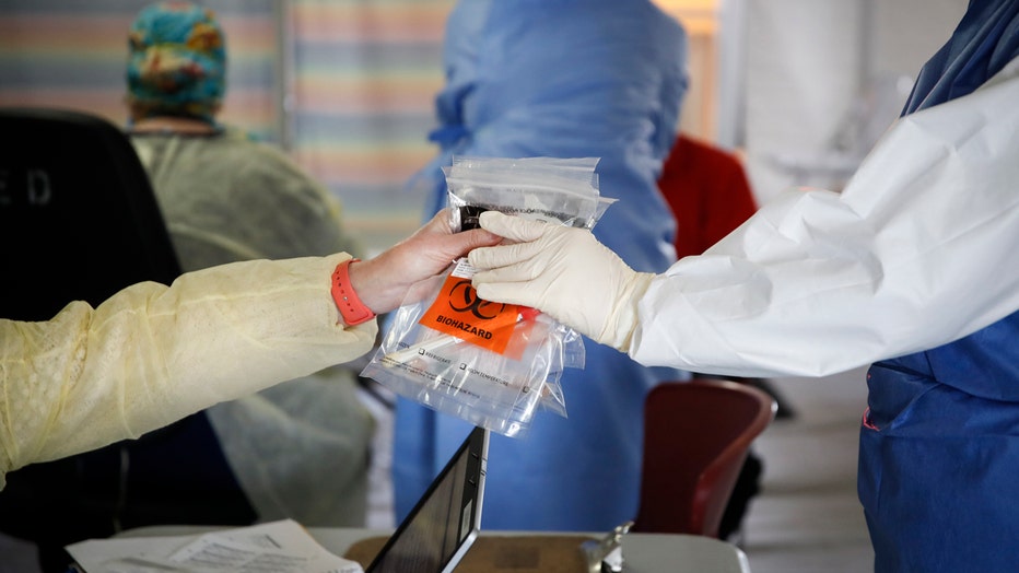 Person hands bags of testing samples to another person