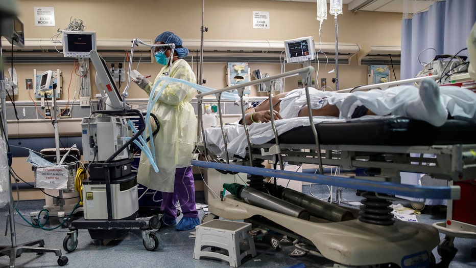Hospital worker operates a ventilator next to a patient