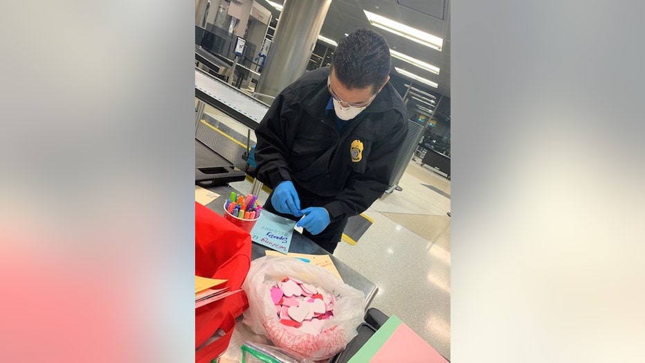 TSA officer wearing a mask makes a greeting card