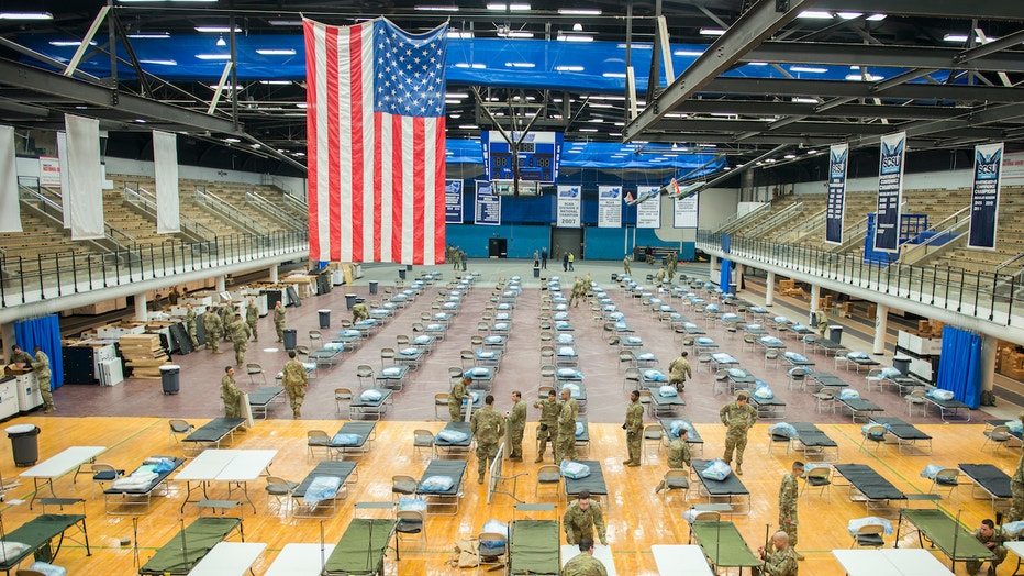 National Guard troops set up medical equipment inside a college sports arena