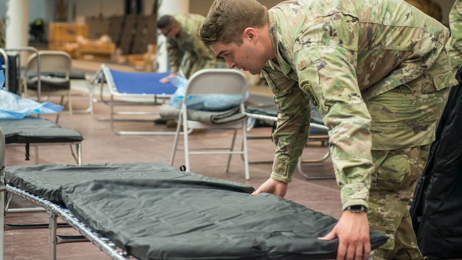 Soldier sets up a field hospital bed inside a college sports arena