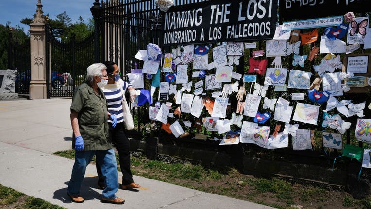 People walk by a memorial for those who have died from the novel coronavirus outside Green-Wood Cemetery on May 27, 2020 in the Brooklyn borough of New York City.