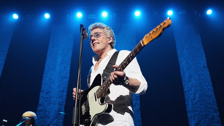 Roger Daltrey holding a guitar performs on stage