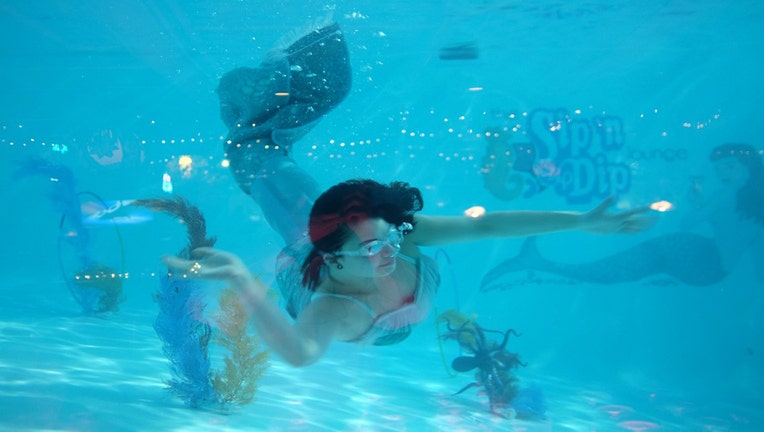 A woman wearing a mermaid costumer swims underwater in a pool