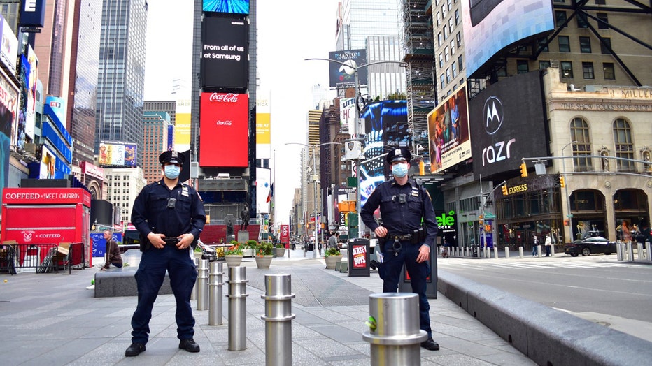 2 officers wearing masks pose for a photo in Times Square
