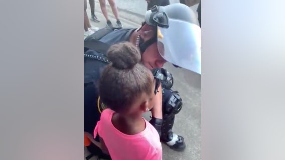 Police officer comforts crying little girl who asked 'are you gonna shoot us?' during protest