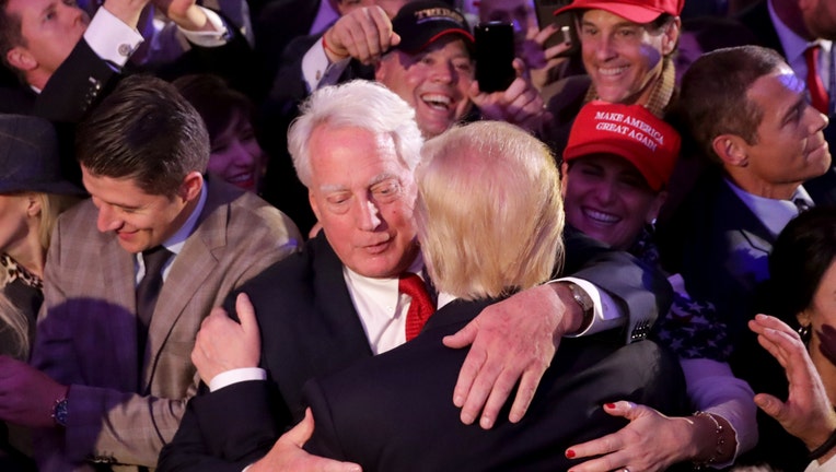 Robert Trump and Donald Trump hug amid a sea of supporters