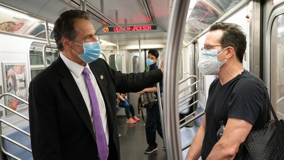 Governor and subway rider stand facing each other inside a subway car