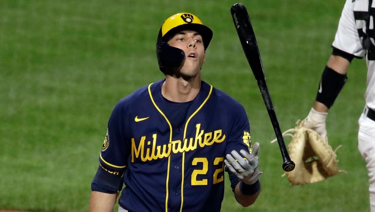 Wearing a blue and yellow Brewers uniform, Christian Yelich flips his bat