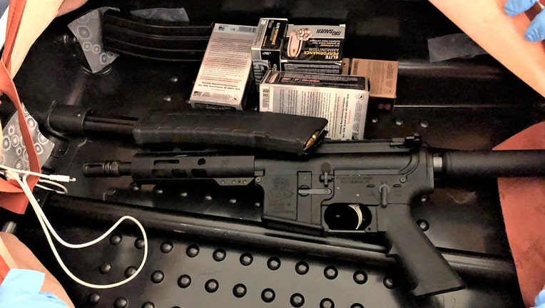 Black tactical rifle, magazines, and boxes of ammunition inside a suitcase