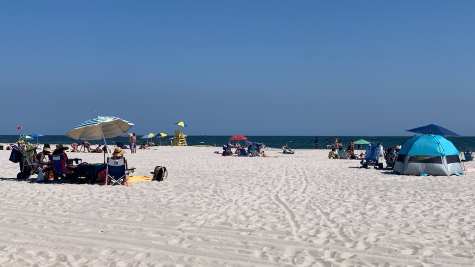 Beachgoers on towels and under umbrellas looking toward the Atlantic Ocean