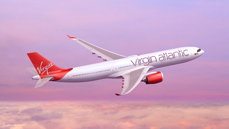 Red and white Virgin Atlantic jetliner flying above the clouds