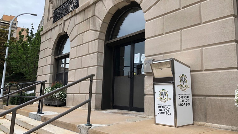 White ballot box at the top of stairs outside a building
