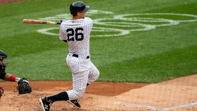 Player in blue-and-white Yankees pinstripes swings through after connecting with a baseball