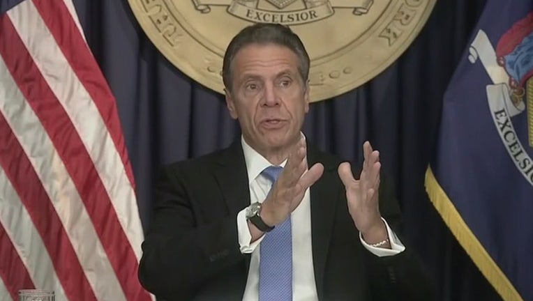 Andrew Cuomo gestures while speaking in front of US and New York flags