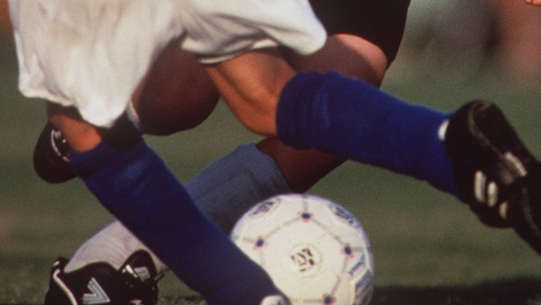 Young boys legs around a soccer ball