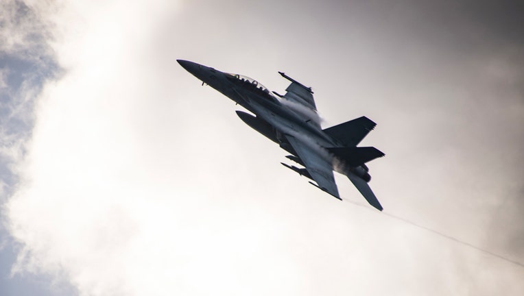 Fighter jet in the sky with clouds in background