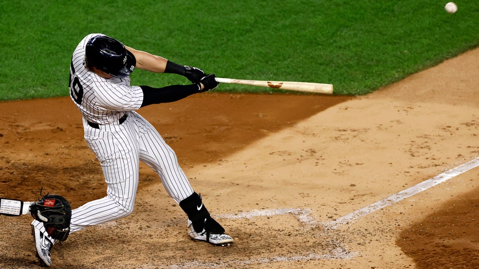 Player in blue-and-white Yankees pinstripes swinging baseball bat