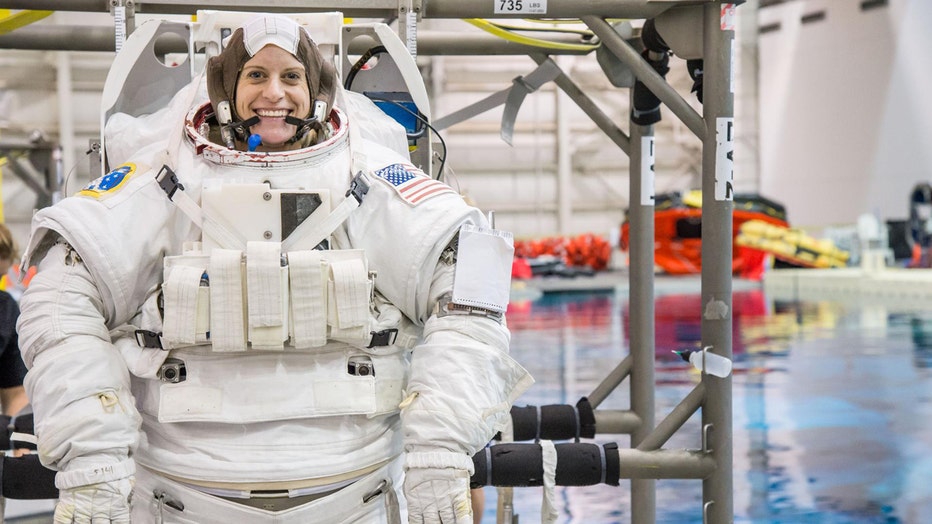 An astronaut in a bulky suit next to a pool