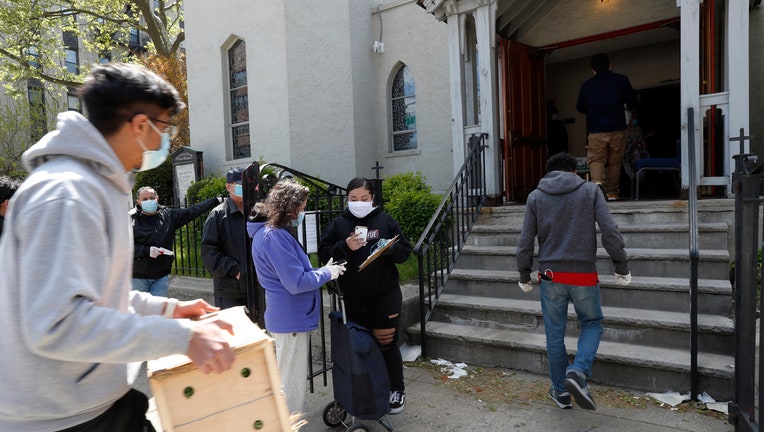 People wearing masks carry boxes of food into a church