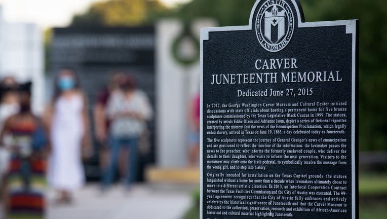 A sign dedicated to information about the Carver Juneteenth Memorial.