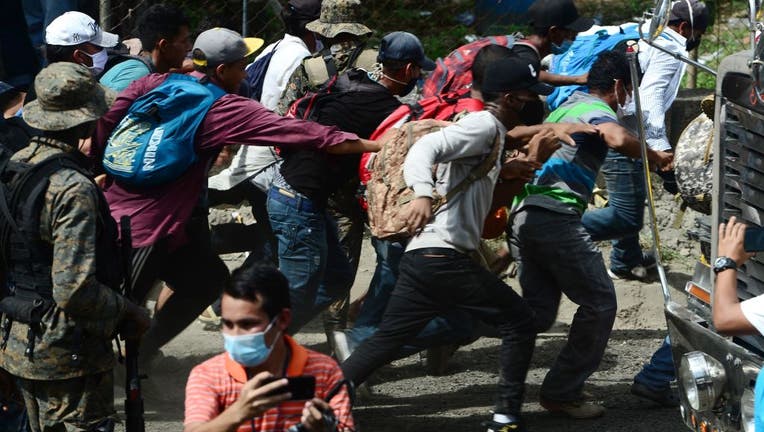 Migrants break a police fence to enter Guatemala on the way to the US.