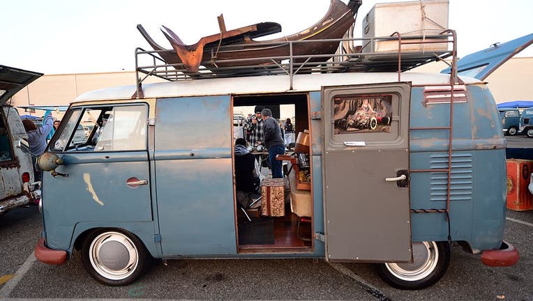 People make trades on parts beside a 1959 Volkswagen Kombi.