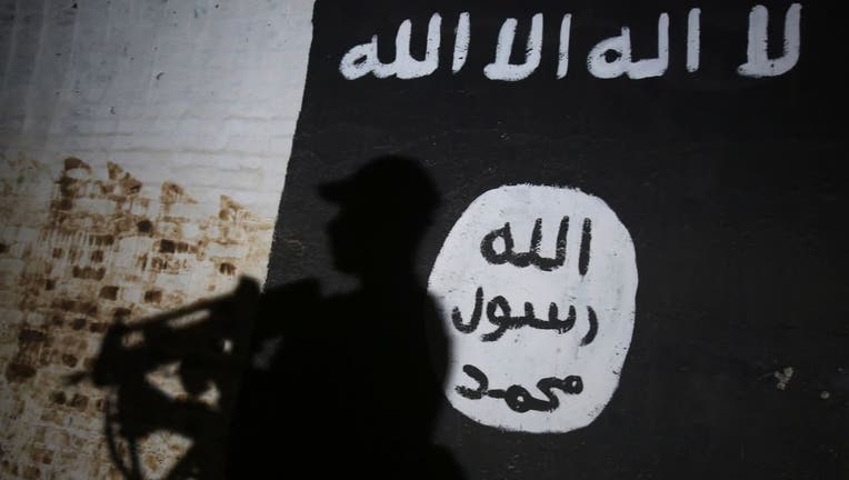 A member of the Iraqi forces walks past a mural bearing the logo of the Islamic State (IS) group on the southern outskirts of Mosul.