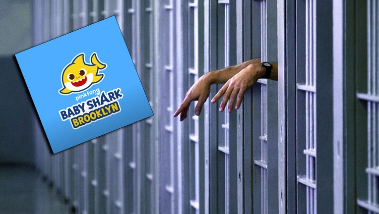 Inmate's hands visible through bars in a jail cell; colorful logo of Baby Shark