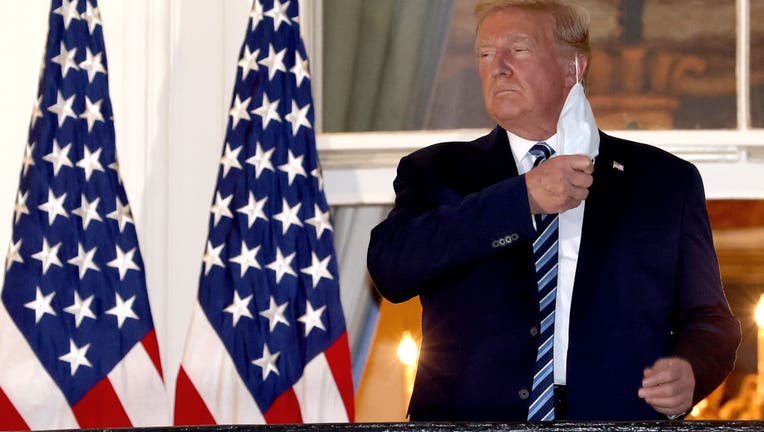 U.S. President Donald Trump removes his mask.