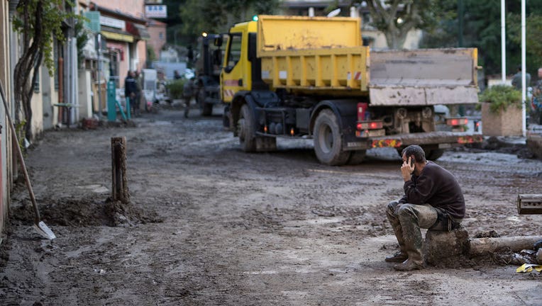 A resident takes a break from clearing mud from a property, in Breil-sur-Roya, near the border with Italy, Monday, Oct. 5, 2020. Flooding has devastated mountainous areas in France's southeastern region of Alpes-Maritimes and Italy's northwestern regions of Liguria and Piedmont, after a storm swept through the two countries on Friday and Saturday. (AP Photo/Daniel Cole)