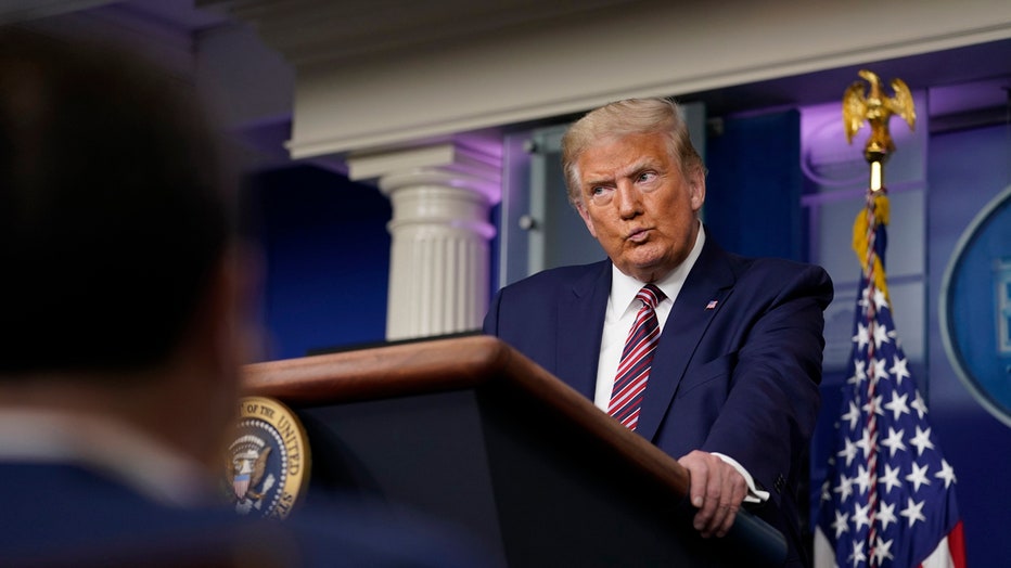Trump holds the edges of the lectern in the White House briefing room